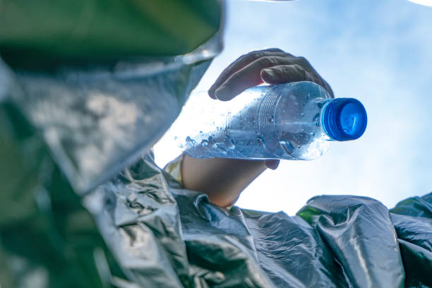 istock Close up of a hand dropping a used bottle in a bin. 1393304520
