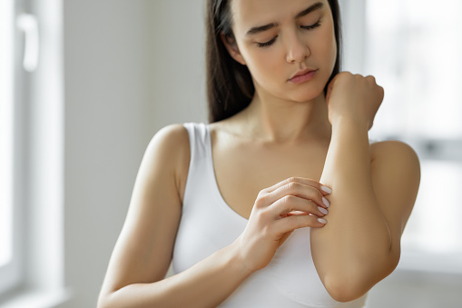 Young woman scratching her arm