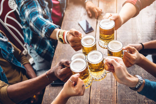 Group of people enjoying and toasting a beer in brewery pub - Friendship concept with young people having fun together stock photo