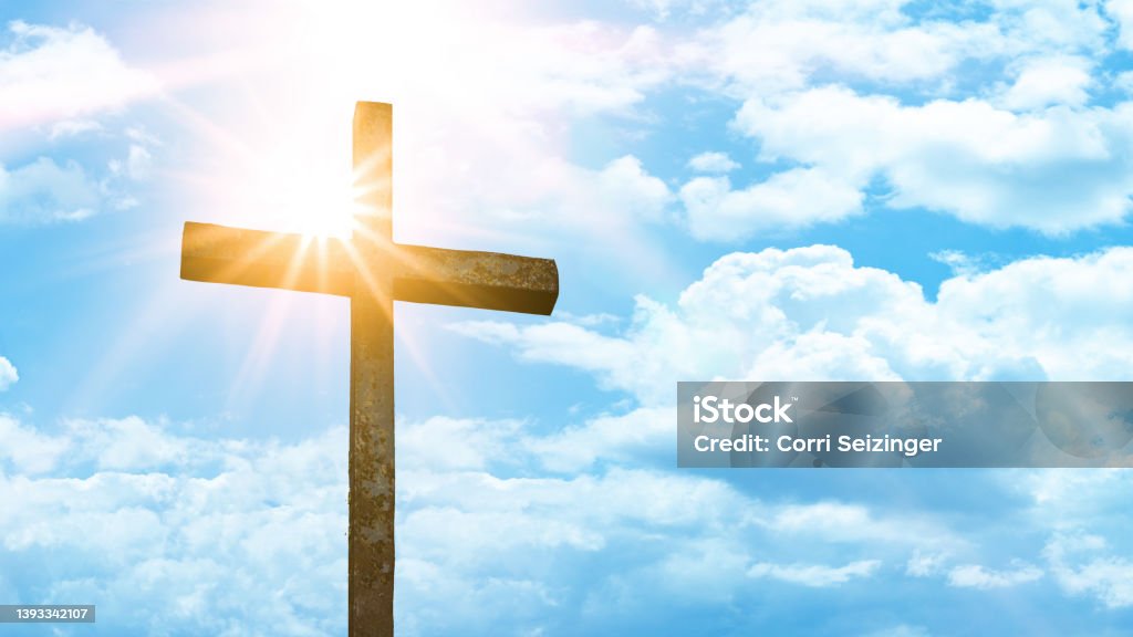 Religious Background - Old steel cross with blue sky, clouds and sunbeams Religious Cross Stock Photo