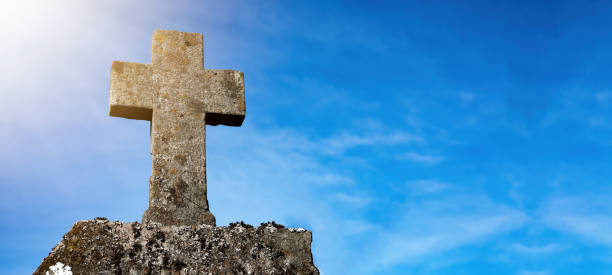 istock Religious Background - Blue cloudy sky withold weathered stone cross, illuminated by the sun 1393342854