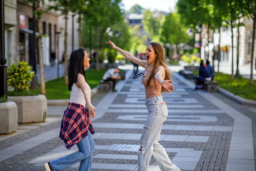 Two friends girl meeting in the street of the city and hugging. friendship, happiness concept