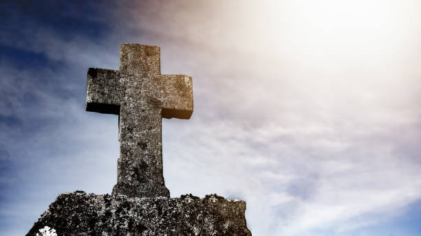 istock Religious Background - Blue cloudy sky withold weathered stone cross, illuminated by the sun 1393342884