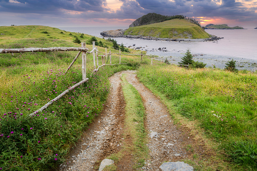 Old wooden fence leading to beach with islands in the distance in Tors Cove, Newfoundland, canada.