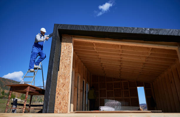 istock Builder installing corrugated iron sheet used as facade of future wooden frame house. 1393346924