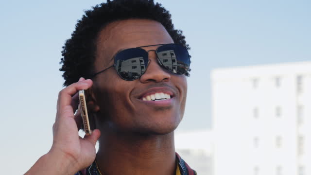 Smiling young man in sunglasses talking on smart phone