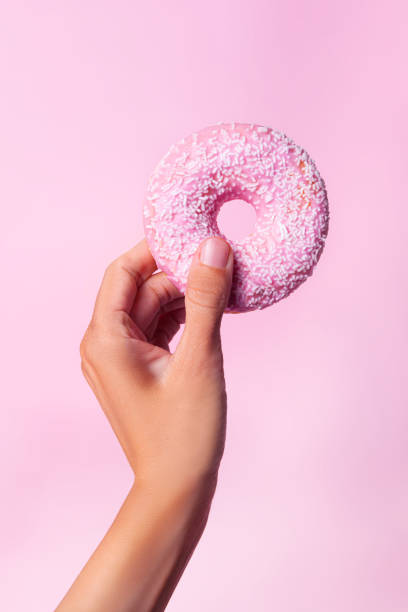 istock close-up hand holding pink donut 1393352210