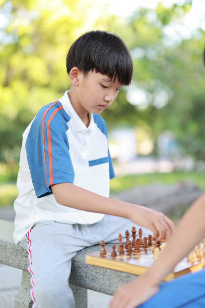 Children started the classic a chess match outdoors Children playing with chess in the park chess stock pictures, royalty-free photos & images