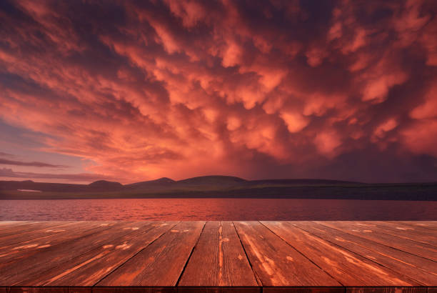 After the storm. Beautiful red clouds over the lake after rain with empty wooden table. Natural template landscape stock photo