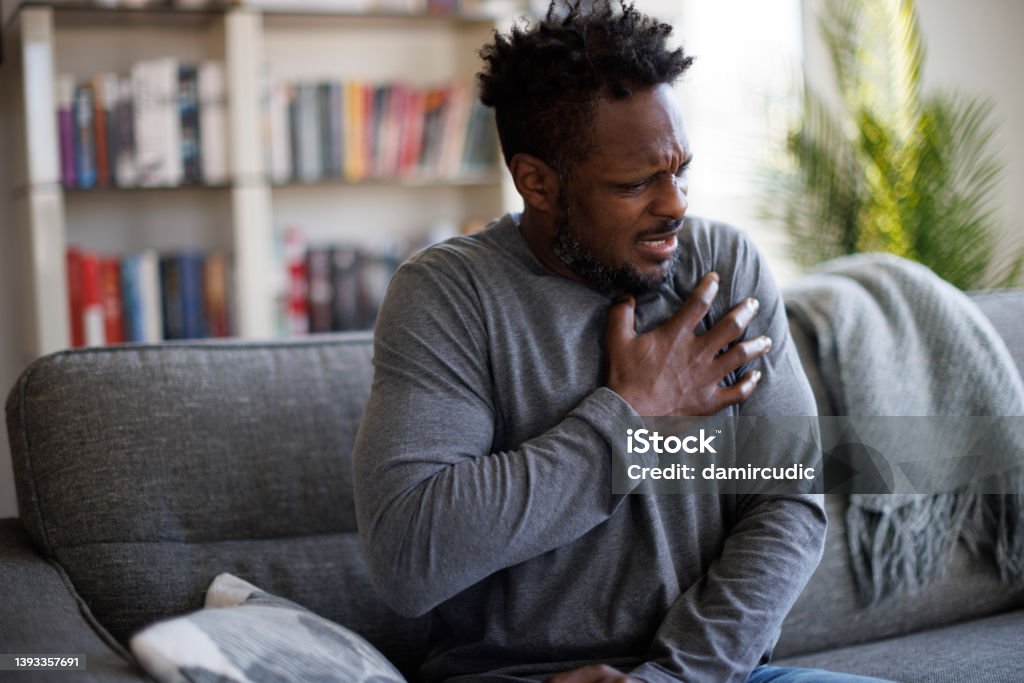 Close-up photo of a stressed man who is suffering from a chest pain and touching his heart area Infarction Stock Photo