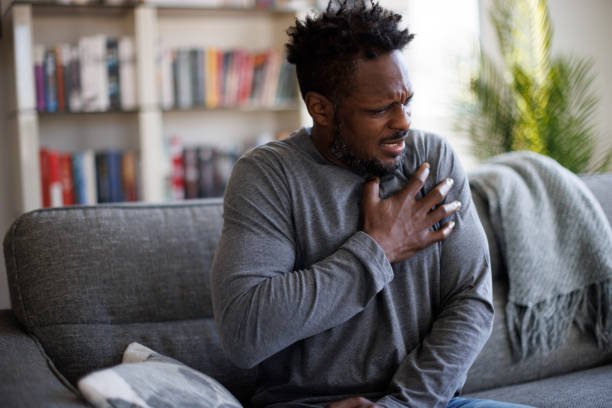 close-up photo of a stressed man who is suffering from a chest pain and touching his heart area - chest pain imagens e fotografias de stock