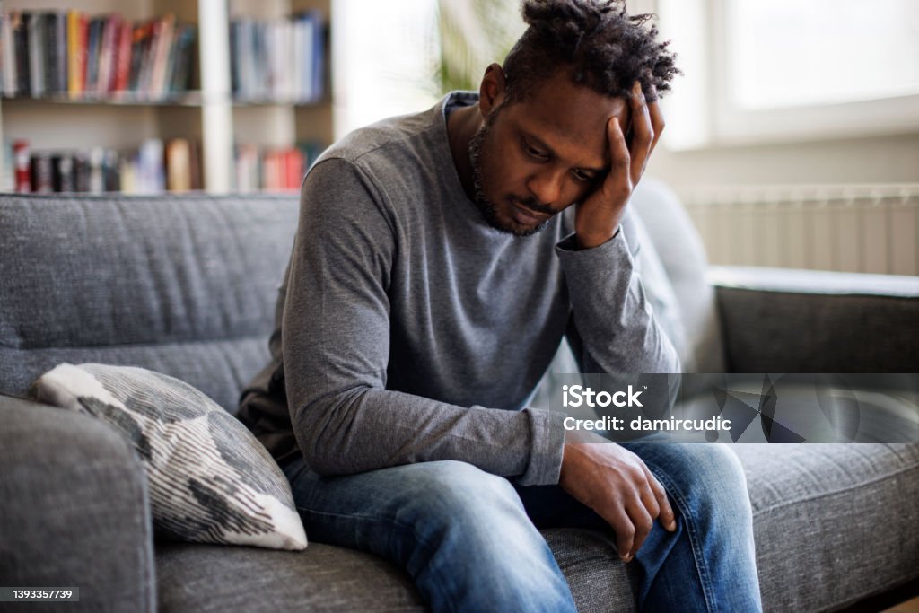 Worried man sitting on couch at home Men Stock Photo