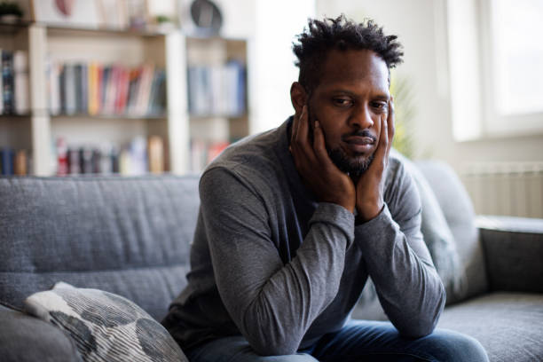 istock Sad man sitting on couch at home 1393357745