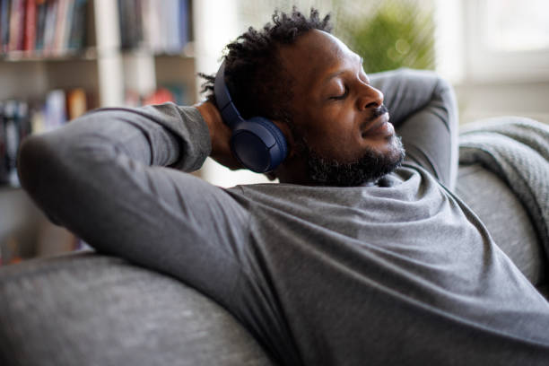 Young man enjoying music over headphones while relaxing on the sofa at home stock photo