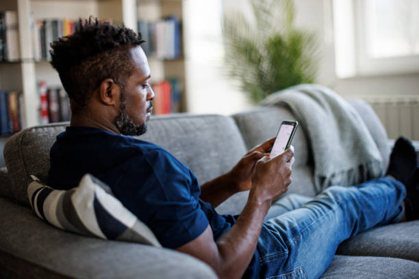 istock Man sitting on couch and sending text message on phone 1393357843