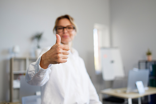 Cheerful woman office worker showing thumbs up. Business lady approves