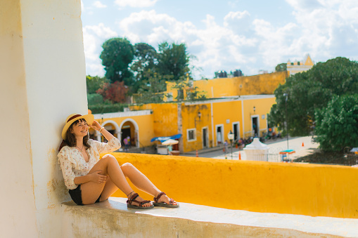 Young Caucasian woman sitting and looking at  Izamal town in Mexico