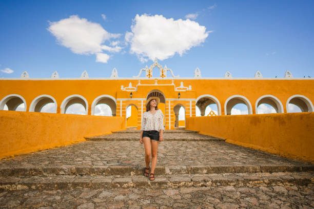 donna che cammina nella città di izamal in messico - women rear view one person arch foto e immagini stock