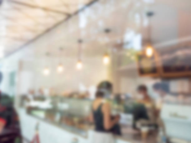 istock Abstract blurred background inside the coffee shop and the counter bar. Blurry bright cafe with people and hanging lamp with bokeh light. 1393367212