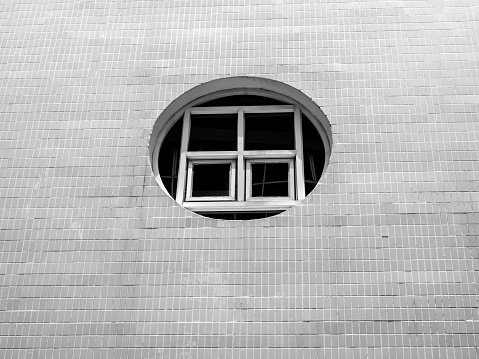 Old round window on white clean outdoor building with mosaic wall, view from outside, minimal style.