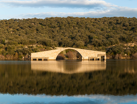 Roman bridge of Guijo De Granadilla over the Alagon river, horizontal, without function flooded blue sky