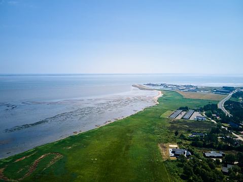 Aerial view of seascape and green landscape against clear blue sky during sunny day