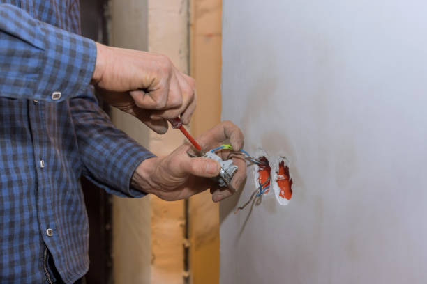 istock Electrician installs lighting switch in the wall 1393380479