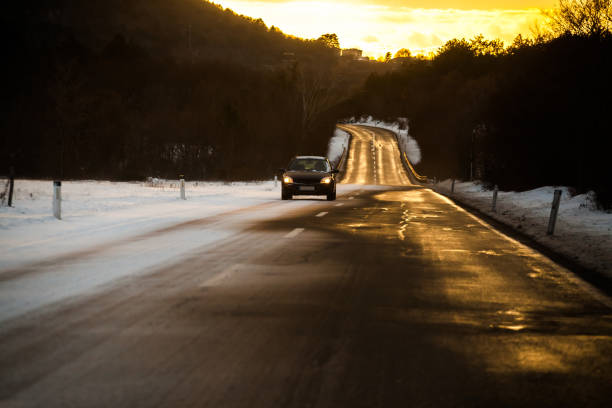 Black car on a winter road through a iced snow .