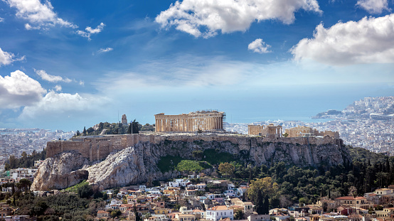 Athens, Greece. Acropolis and Parthenon temple landmark. Ancient remains, aerial view from Lycabettus Hill. Urban cityscape, blue sea and cloudy sky background