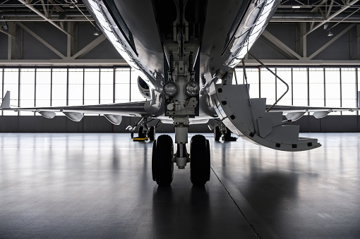 Luxury business jet airplane being stored inside an aviation hangar. Landing gear view