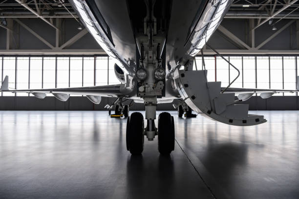 Luxury private jet plane in aviation hangar Luxury business jet airplane being stored inside an aviation hangar. Landing gear view fuselage stock pictures, royalty-free photos & images