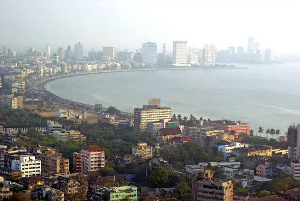 Aerial view of south Mumbai skyline in late afternoon mist showing elite Marine Drive stretch enveloping the Arabian sea in a beautiful arc and Nariman Point, gymkhanas (open spaces reserved for sports)