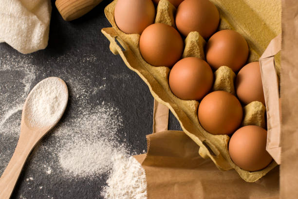 istock Natural fresh chicken eggs in eco package, flour on a dark kitchen table, linen towel. Traditional ingredients for baking. Top view. Flat lay. Kinfolk style. 1393392941