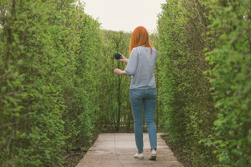 Female trying to find way out from a maze hedge with string