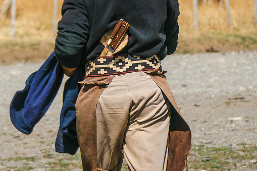 The costume of a gaucho, still worn by modern Argentine cowhands, included a chiripa girding the waist, a woolen poncho, and long, accordion-pleated trousers, called bombachas, gathered at the ankles and covering the tops of high leather boots. \nPhoto was made in Los Glaciares National Park, Patagonia, Argentina