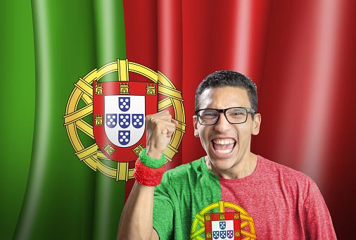 Soccer fan national team of Portugal celebrating goal in front of flag
