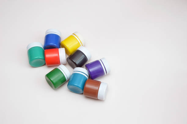 Closed jars with gouache of different colors on a light background. Creativity, hobby.