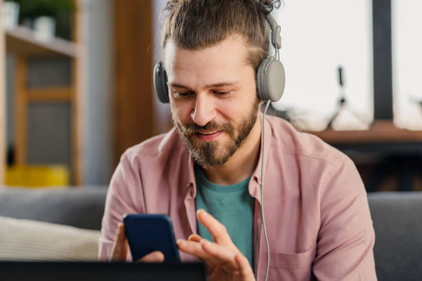 istock n the headphones with a smartphone in his hand using a laptop computer. Online banking 1393401225