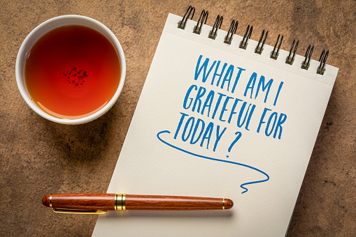 what am I grateful for today  - inspirational question in a notebook with a cup of tea, gratitude and personal development conscept