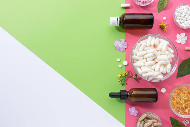 composición plana de varias cápsulas vitamínicas y suplementos dietéticos sobre fondo verde, rosa y blanco con espacio de copia. concepto de productos alimenticios. - snap fotografías e imágenes de stock