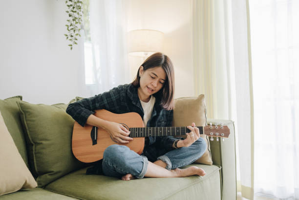 istock Girl playing guitar in room. Musician practicing music on string instrument 1393405413