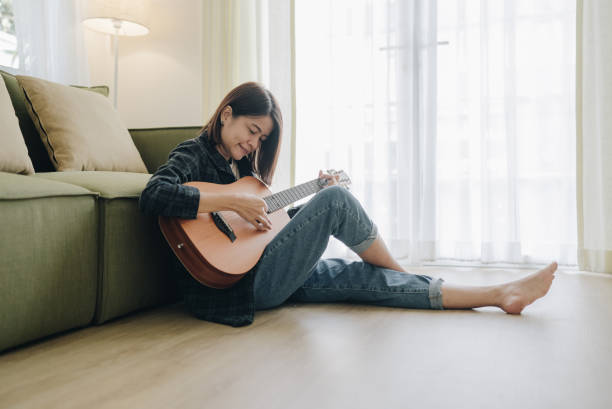 istock Girl playing guitar in room. Musician practicing music on string instrument 1393405425