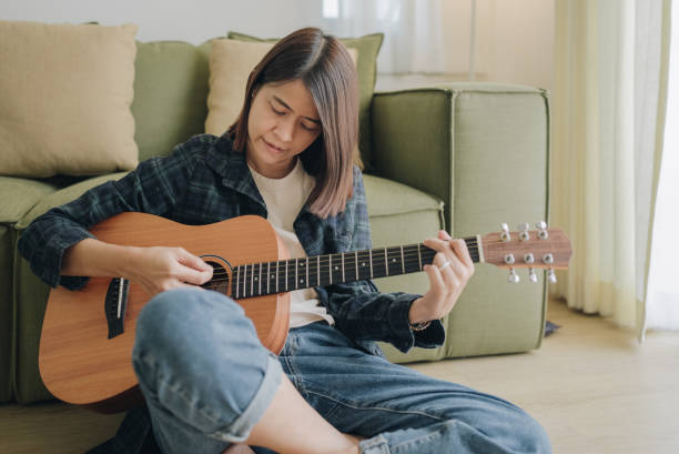 istock Girl playing guitar in room. Musician practicing music on string instrument 1393405452