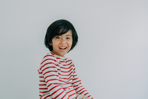 Portrait of a happy asian boy looking at the camera smiling over a white background