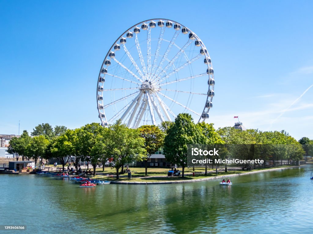 Montreal Ferris wheel in the Old port. La Grande Roue de Montreal. Montreal Ferris wheel in the Old port. La Grande Roue de Montreal. Pedal boats on the river. Montréal Stock Photo