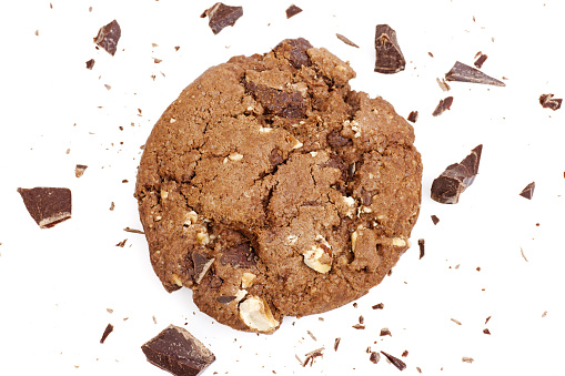 Cracked biscuit, pieces of chocolate and crumbs on white background. Horizontal photo.