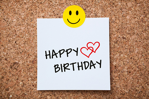 White Sticky Note With Happy Birthday And Red Push Pin On Cork Board