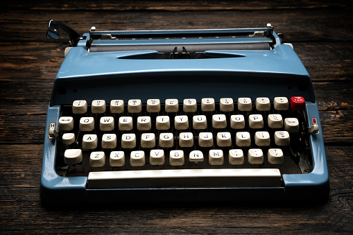 A classic style typewriter which is placed on working desk. Equipment object photo. Close-up and selective focus.