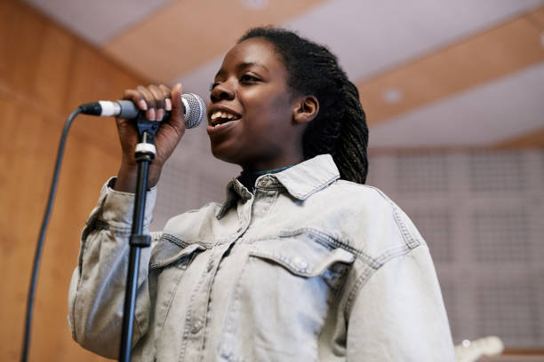 istock Young Woman Singing in Recording Studio 1393425442