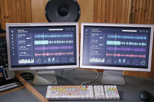 Background image of two computer screens with audio tracks in home recording studio, music production concept